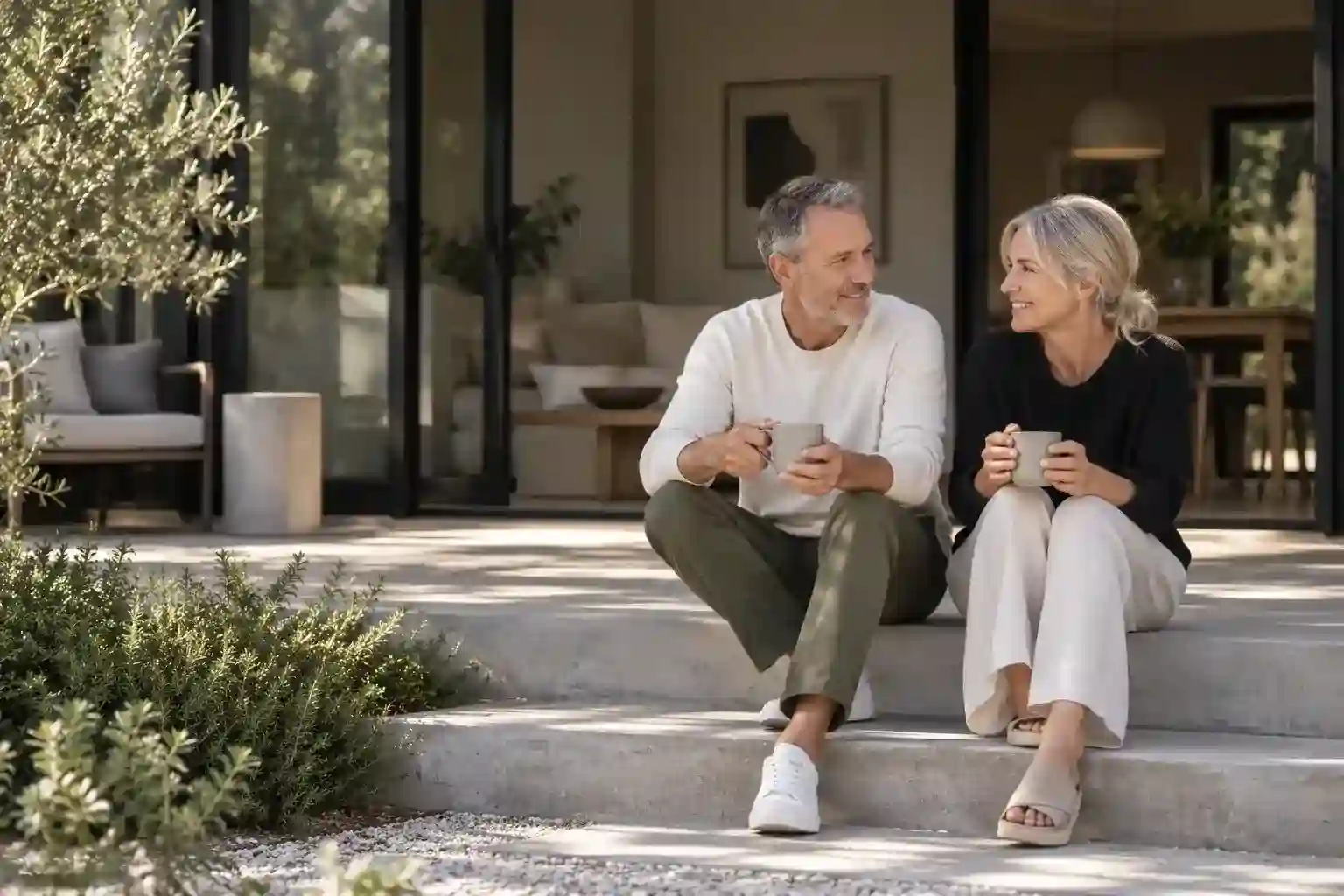 Couple sitting on home steps with coffee cups illustrating financial goals