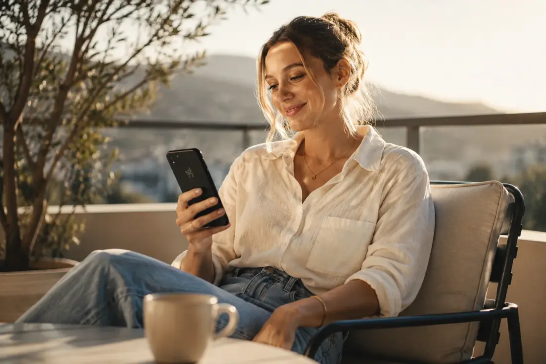 Woman relaxing on a balcony checking her phone