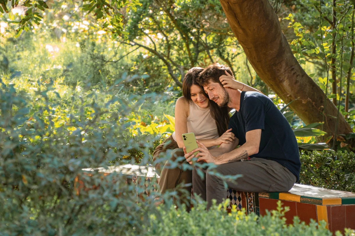 A couple on a garden bench looking at a phone together