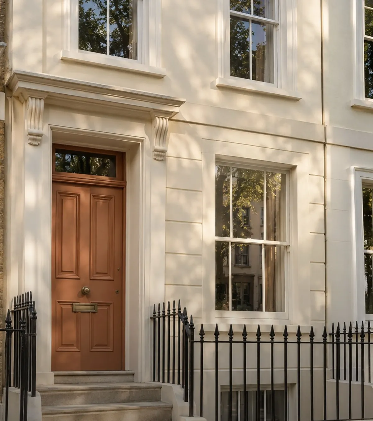 The front of a cream-painted townhouse with a wooden door